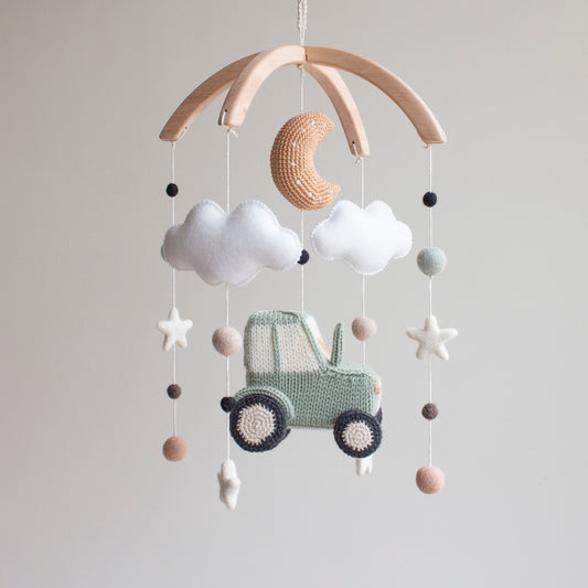 Detailed shot of a tan crochet crescent moon and soft white wool felt stars on an artisan mobile.