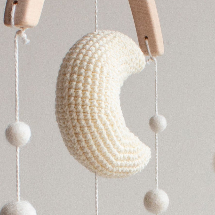 Crochet crescent moon and soft white stars on a golden retriever nursery mobile.