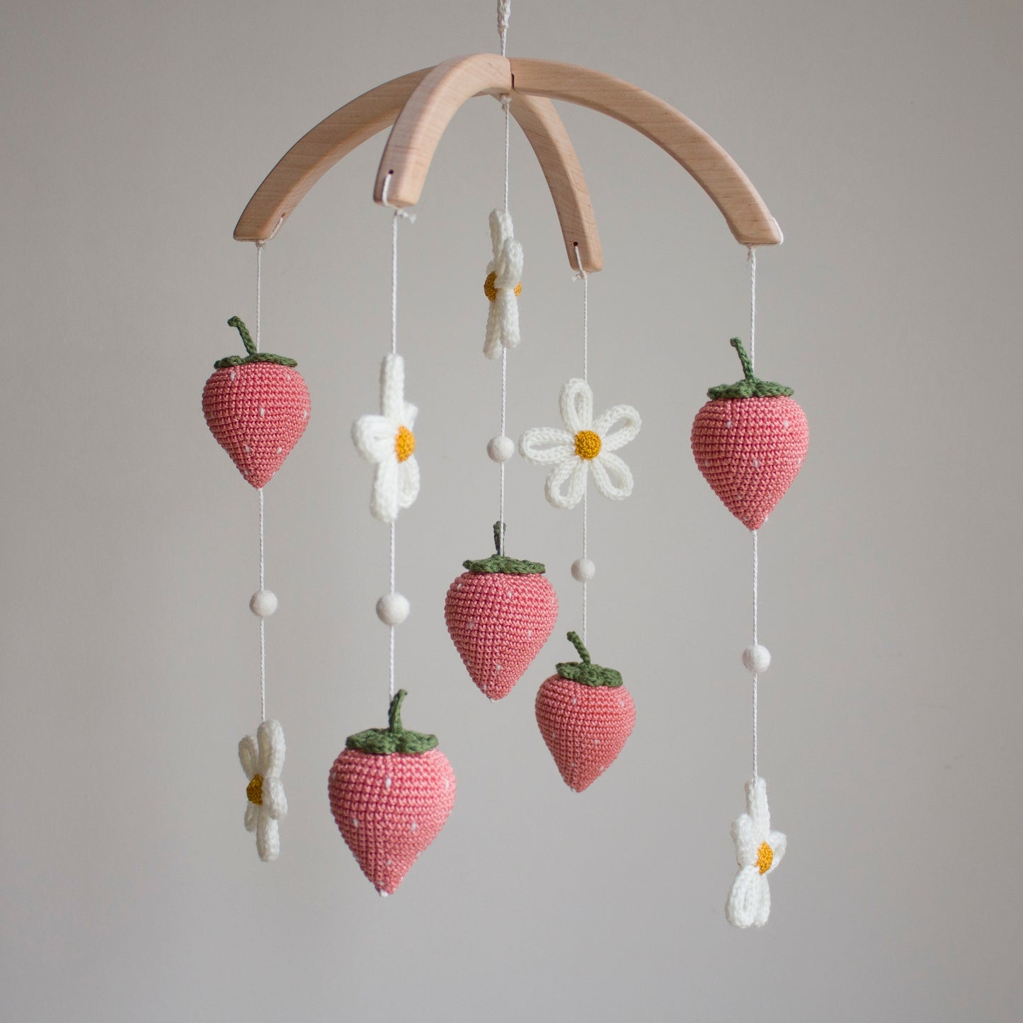 High-contrast coral fruit and white floral elements designed to support infant visual stimulation. Whimsical floral garden nursery mobile hanging in a modern baby room above a white wooden crib.