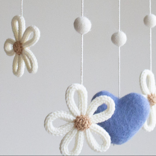 Close-up of knitted daisy petals and soft royal blue felted heart