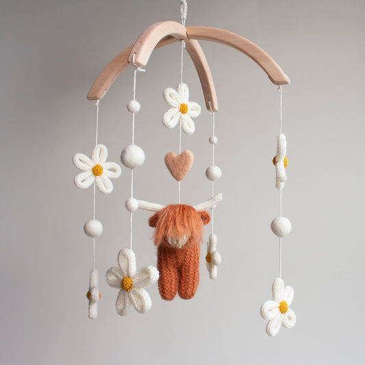 Ethical nursery decor featuring a rust highland cow and ivory daisies, handcrafted with 10 years of artisan expertise. This high-quality baby mobile uses certified non-toxic wool to ensure safety for the baby’s space. A prestigious gift choice for aunts, grandparents, or friends, it provides the "photogenic moment" modern parents desire while maintaining the high standards of an heirloom-quality, artisan-made product from Northern Ireland.