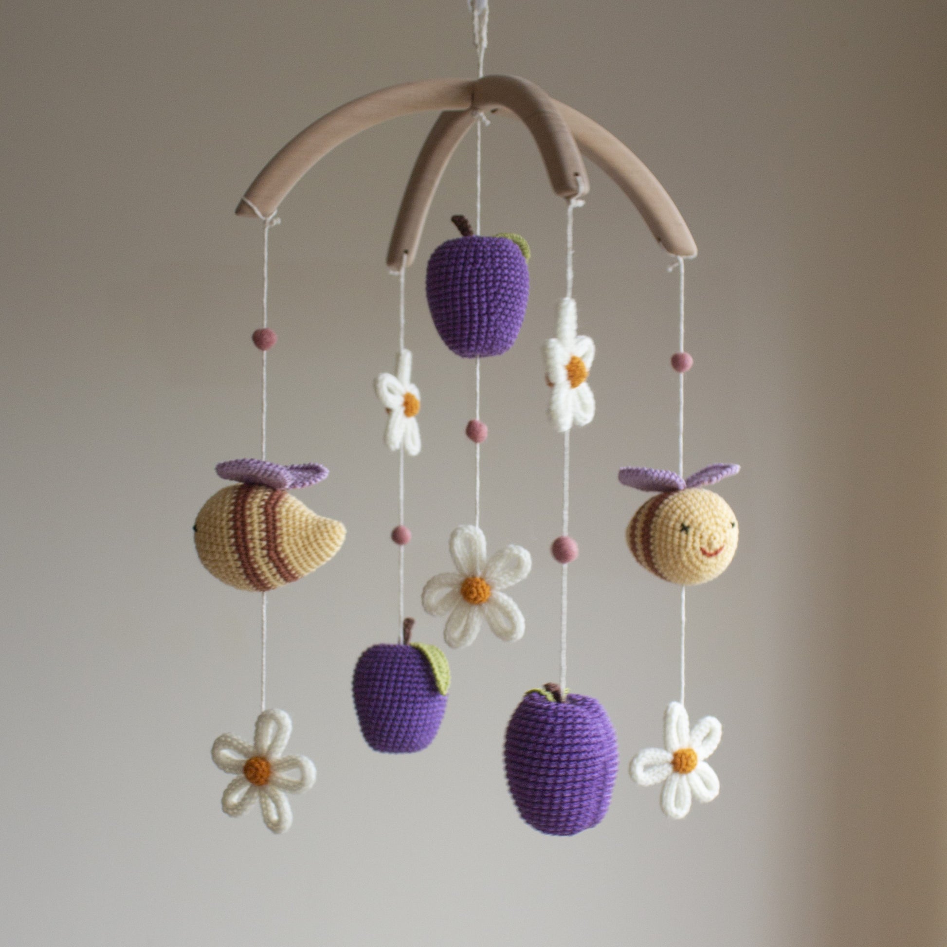 Whimsical fruit garden nursery mobile hanging above a white crib in a bright, modern nursery.