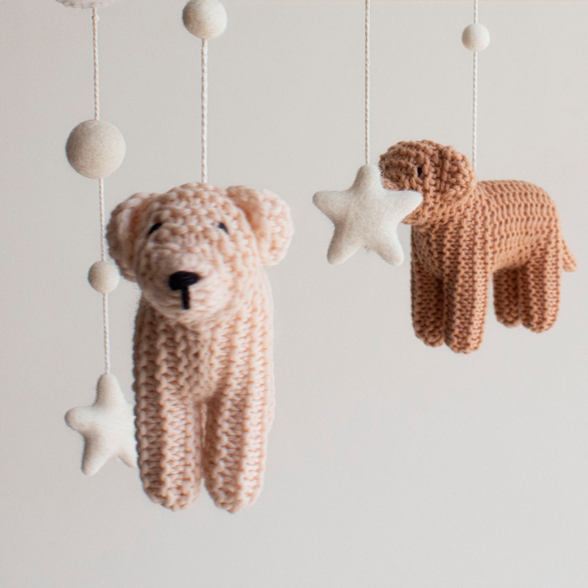 Close up of hand knitted wool dog hanging on a baby mobile. Perfect gft for dog-loving families
