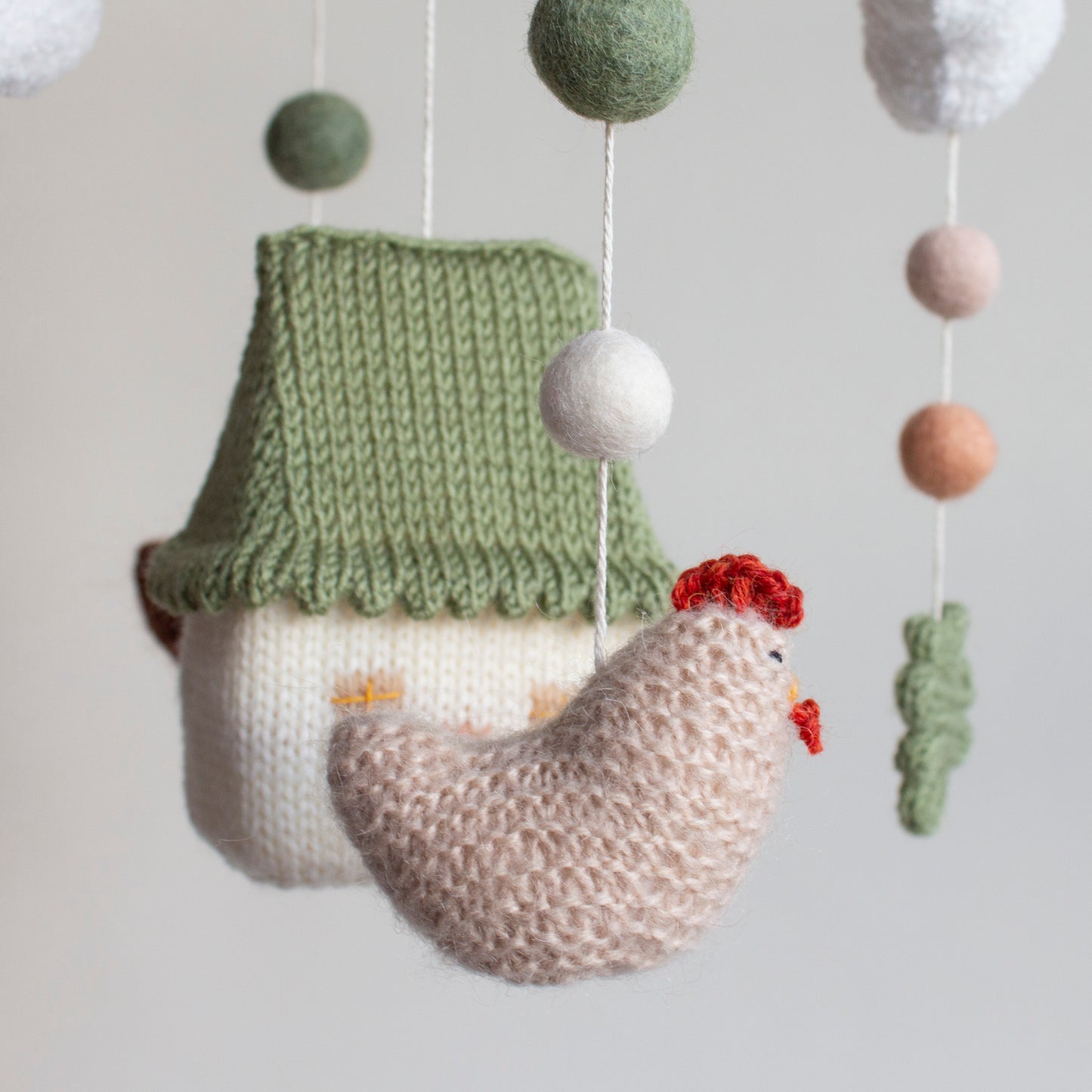 Close-up of hand-knitted beige chicken with red combs for a farm-themed nursery.