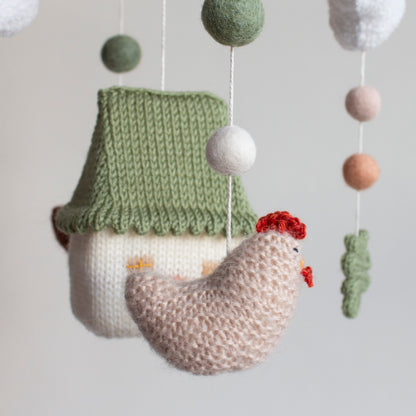 Close-up of hand-knitted beige chicken with red combs for a farm-themed nursery.
