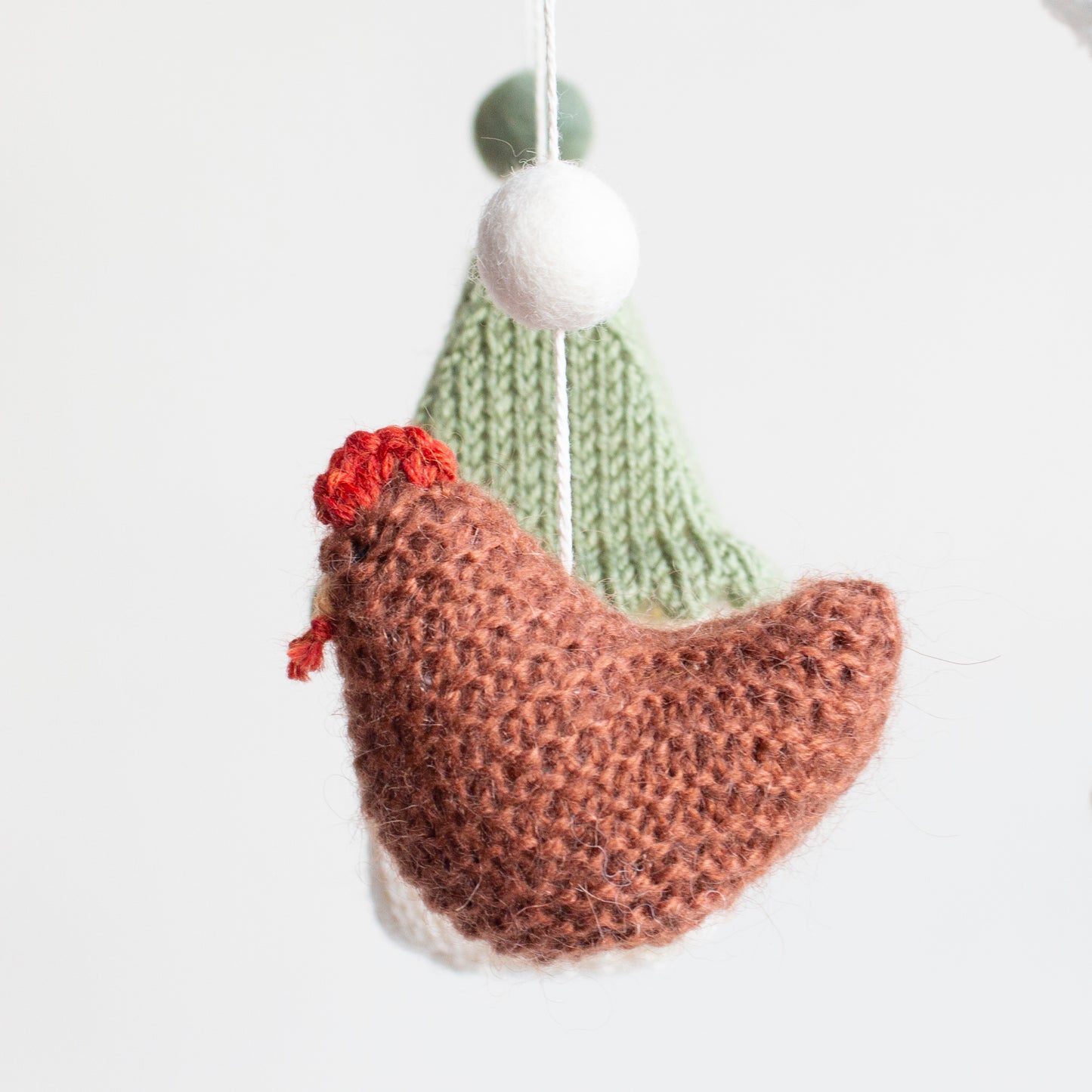 Close-up of hand-knitted cinnamon  chicken with red combs for a farm-themed nursery.