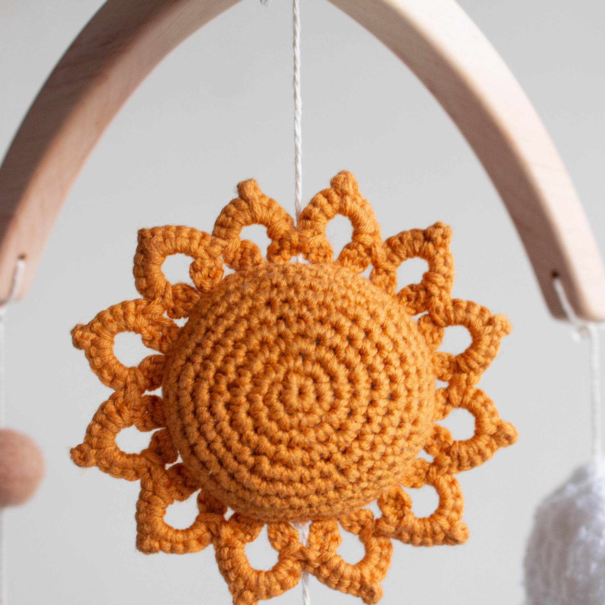Macro view of a crocheted burnt orange sun with intricate ray detailing.
