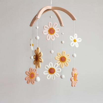 Hand-knitted sunflower baby mobile with yellow petals and white daisies on a wooden hanger.