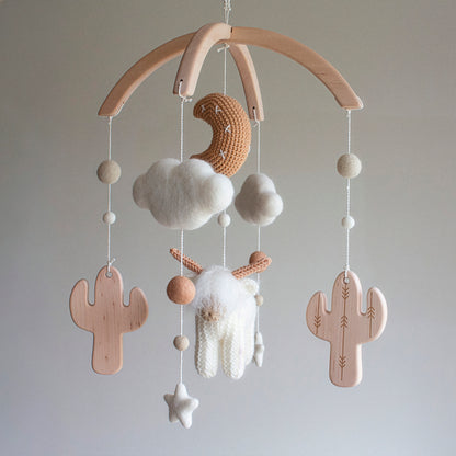 A full view of the White Longhorn Cow Mobile, showcasing the meticulous craftsmanship of the tan moon and shaggy "hairy coo." The mobile uses wool yarn OEKO-TEX Standard 100 safe for infants and features smooth, untreated solid alder wood cactuses. This timeless design creates a serene focal point in any nursery. As a durable heirloom gift, it is a thoughtful choice suitable for different baby gifts, including baby showers and "welcome home" presents for new parents.