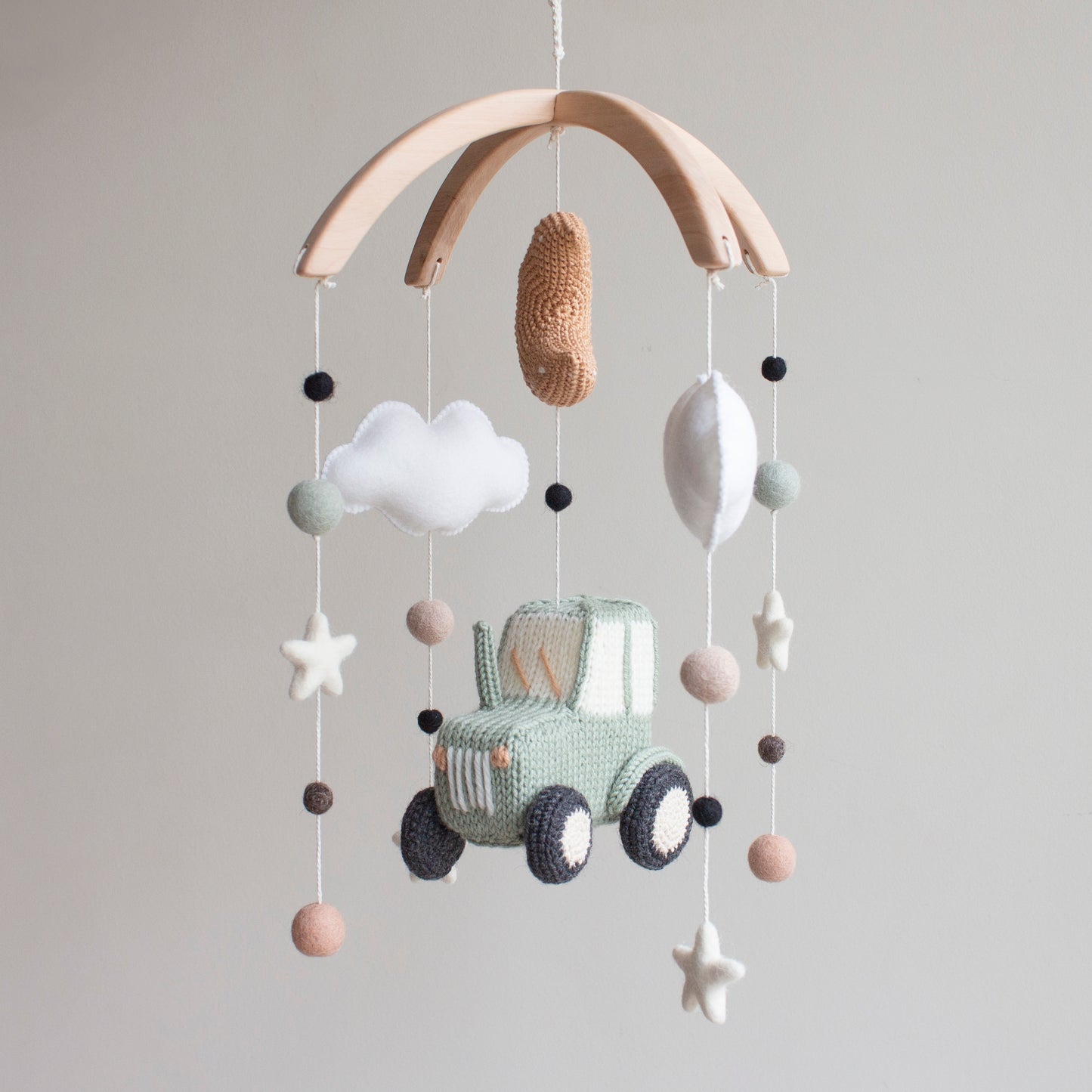 Modern farmhouse nursery mobile hanging above a white crib in a bright, neutral baby room.