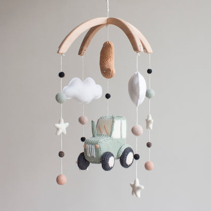 Modern farmhouse nursery mobile hanging above a white crib in a bright, neutral baby room.
