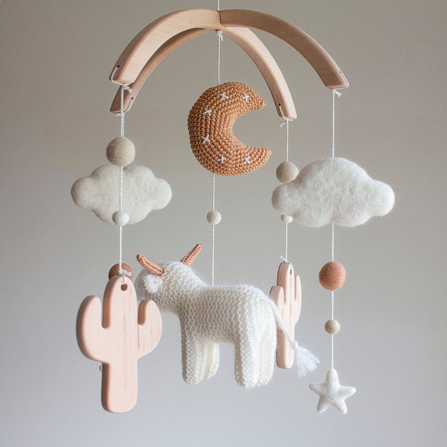 This shaggy white longhorn cow mobile brings the warmth of a rustic retreat to the nursery. Crafted from high-quality wool yarn and an untreated solid wood mobile frame, it features smooth untreated solid wood cactuses that invite curiosity. The "Desert Scandi" palette ensures a timeless design that grows with your child. Ideal as a high-end heirloom gift, this mobile is suitable for different baby gifts, offering a unique story of craftsmanship and connection for the modern family.