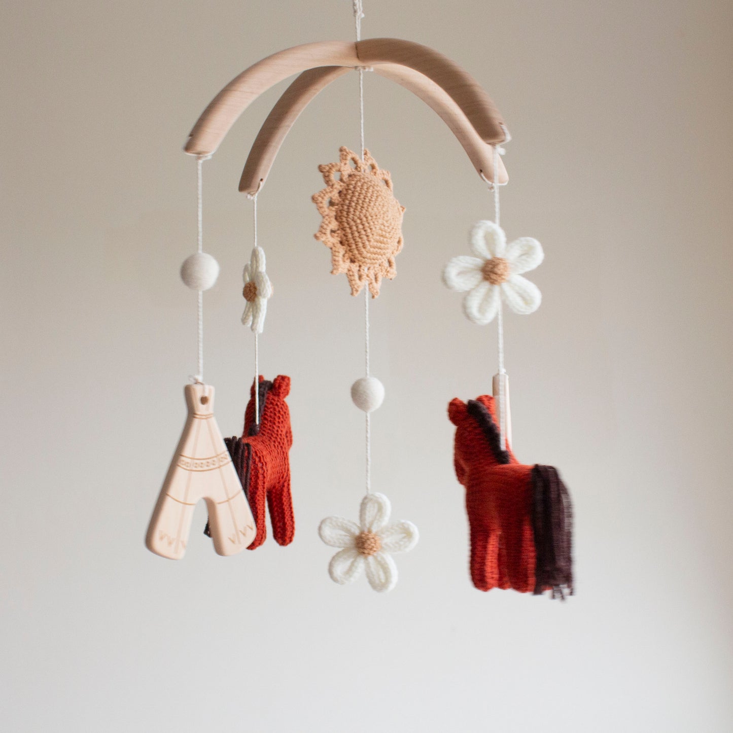 Whimsical floral cowgirl nursery mobile hanging in a modern baby room above a wooden crib.