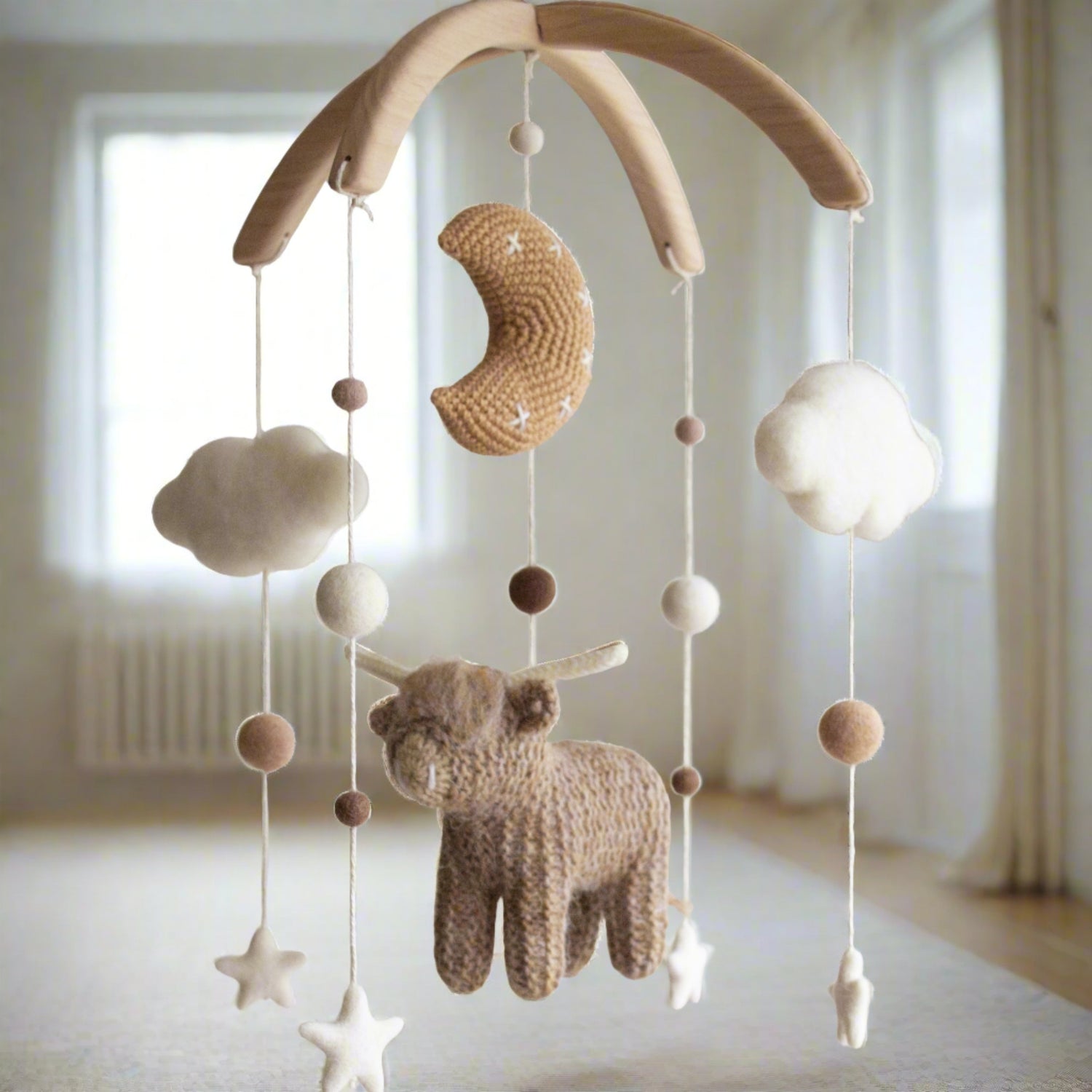 Rustic Western-themed nursery mobile hanging in a modern baby room above a wooden crib.