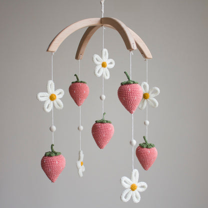 Hand-knitted strawberry and daisy baby mobile with light coral fruit and cream flowers on a wooden arch. Unique baby shower gift—artisan strawberry and daisy mobile handcrafted in Northern Ireland.