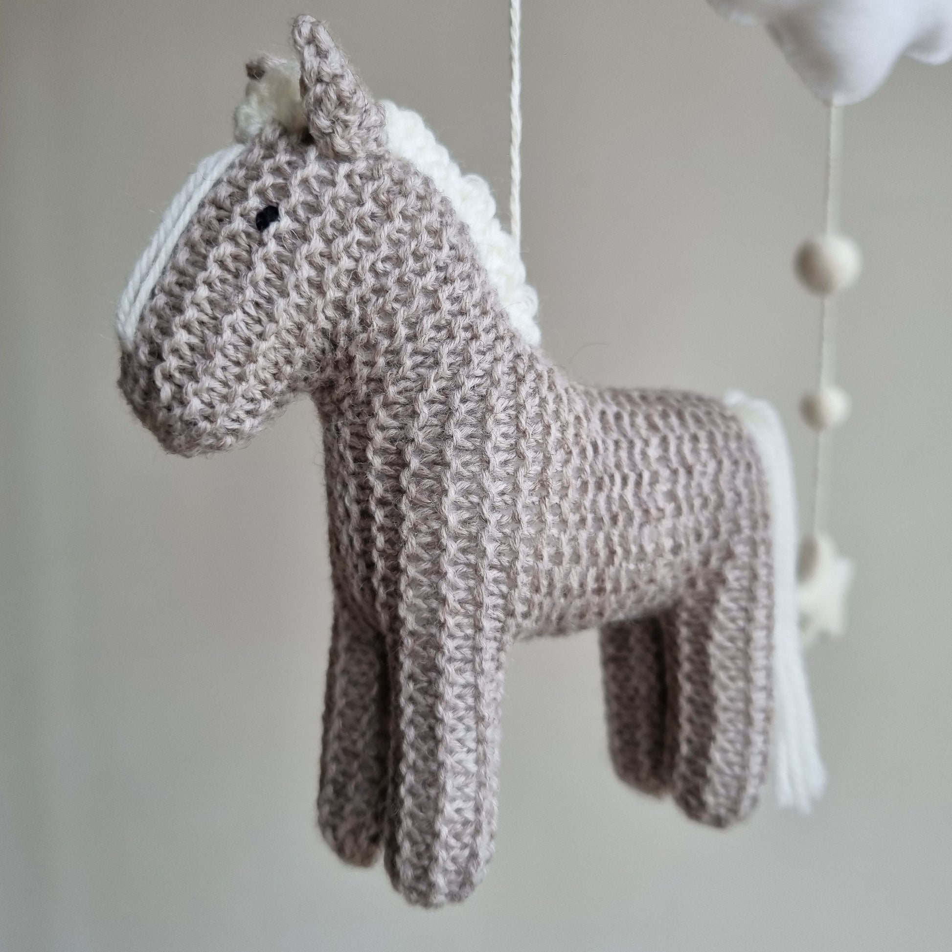 Cloe up of 100% wool knitted texture on grey horse with soft white hair. Gender neutral baby gift