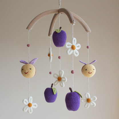 Close-up of a hand-crocheted bee with purple wings and golden-tan yarn for a garden nursery theme.