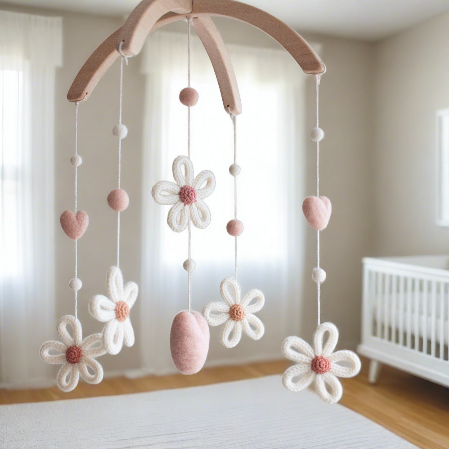 Minimalist floral nursery mobile hanging near  white crib in a sun-drenched room.