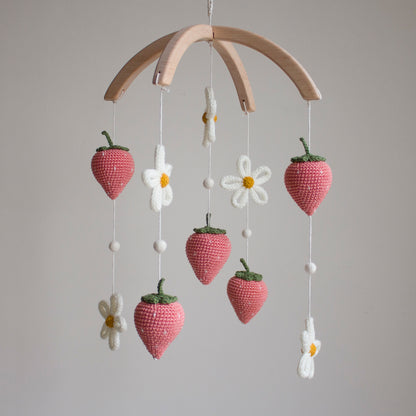 Detailed shot of ivory knitted daisies with golden centers and cream wool accents on a botanical baby mobile. Smooth, hand-sanded untreated alder wood cross-arch hanger for a minimalist nursery mobile.