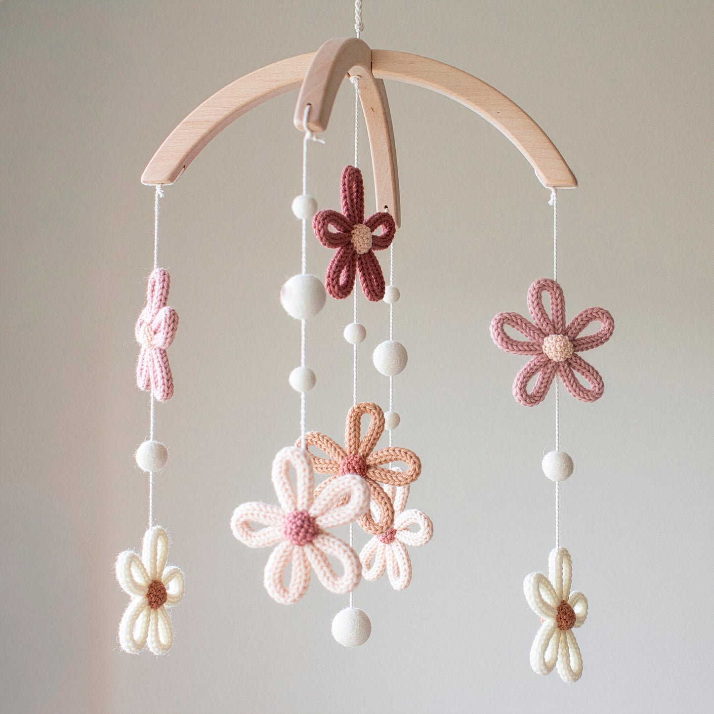 This charming nursery mobile features crochet flowers and felted white wool balls suspended from a cross-shaped wooden hanger. Using wool yarn OEKO-TEX Standard 100 safe for baby environments, it provides a safe, chemical-free atmosphere. The use of untreated solid wood highlights its eco-friendly nature. With its timeless design, this mobile is a top choice for those seeking an heirloom gift or unique baby shower presents that blend beautifully with modern nursery themes.