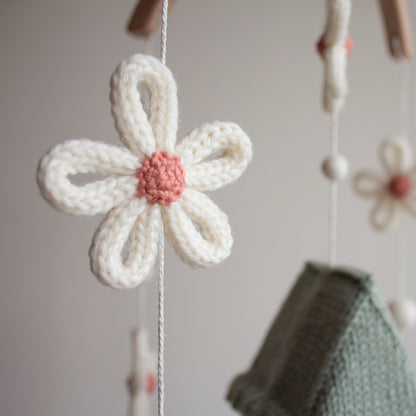 Macro view of 100% wool yarn stitches on a white crochet daisy with a dusty rose center.