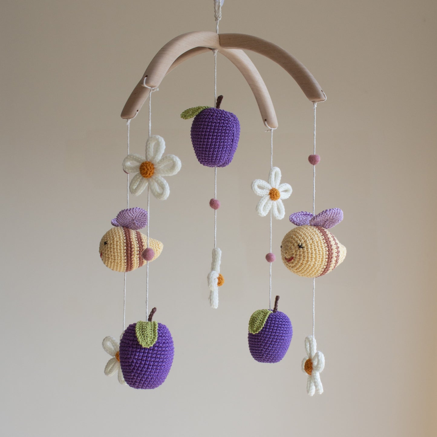 Smooth untreated solid alder wood cross-arch hanger for a minimalist artisan baby mobile. Macro view of a white crochet daisy with a yellow center and 100% cotton yarn texture.