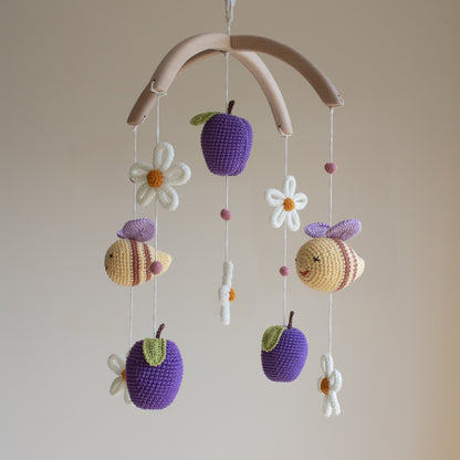Smooth untreated solid alder wood cross-arch hanger for a minimalist artisan baby mobile. Macro view of a white crochet daisy with a yellow center and 100% cotton yarn texture.