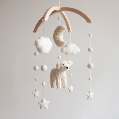 Hand-knitted golden retriever baby mobile with white clouds and crochet moon on a wooden arch.