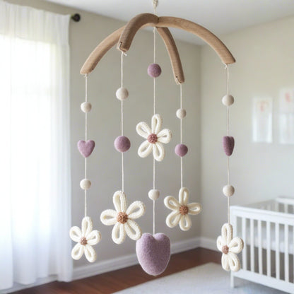 Minimalist floral nursery mobile hanging near  white crib in a sun-drenched room.