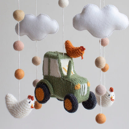 Close-up of a hand-knitted green tractor amigurumi for a farm-themed nursery.