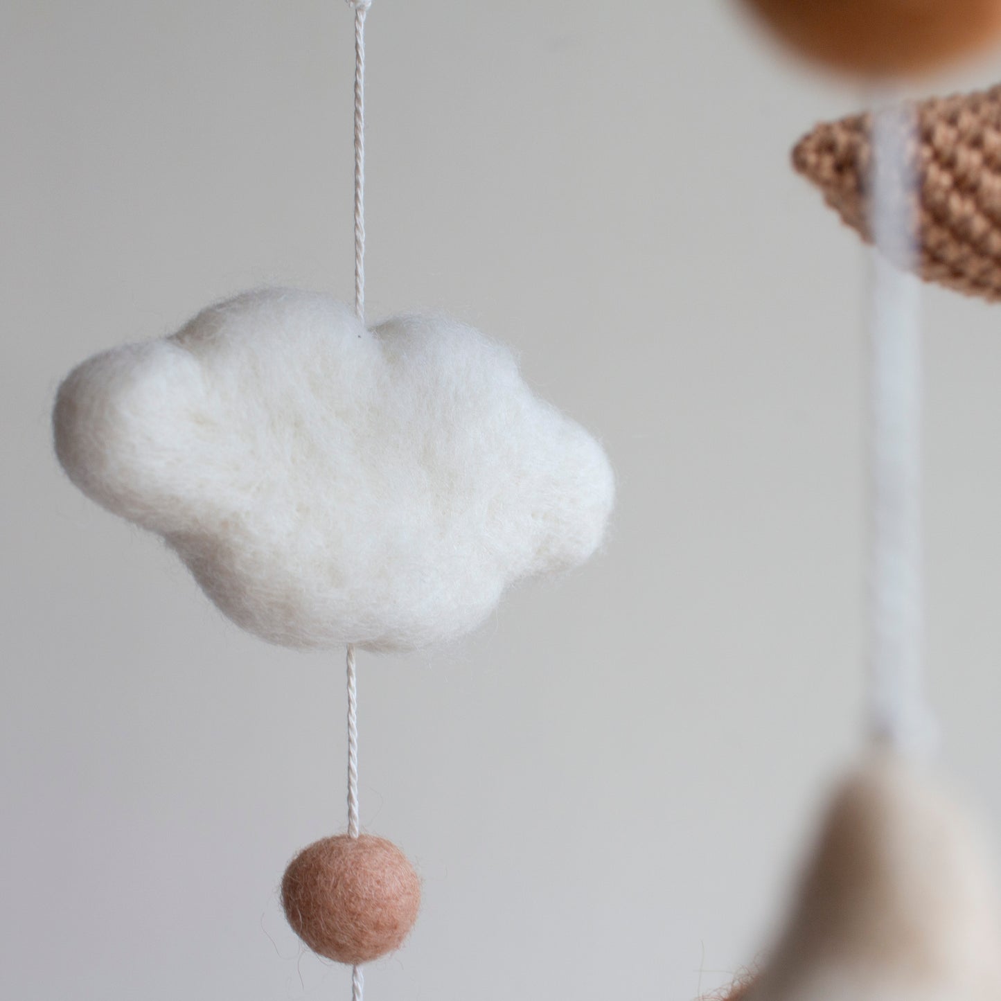 A detailed focus on a soft wool cloud and a felted ball, part of the high-quality, non-toxic materials used in LanaCrocheting nursery decor.