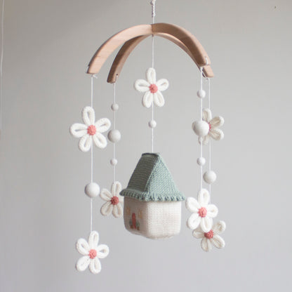 Whimsical floral nursery mobile hanging in a sun-drenched, neutral-toned baby room.