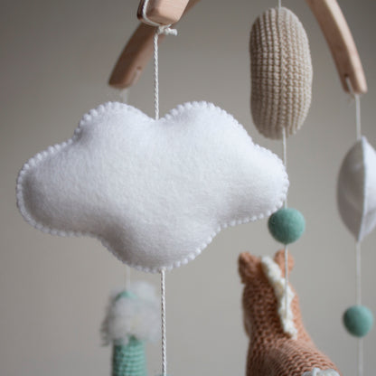 Close-up of a soft wool felt cloud and mint green accent ball on a Western-themed nursery mobile. Each cloud is carefully stitched for an airy and minimalist look, reflecting our commitment to design aesthetics and high-quality craftsmanship. These natural, sustainable elements create a tranquil sensory environment for a newborn, serving as a vetted heirloom gift that demonstrates a belief in ethical sourcing and support for small, independent UK artisan businesses.