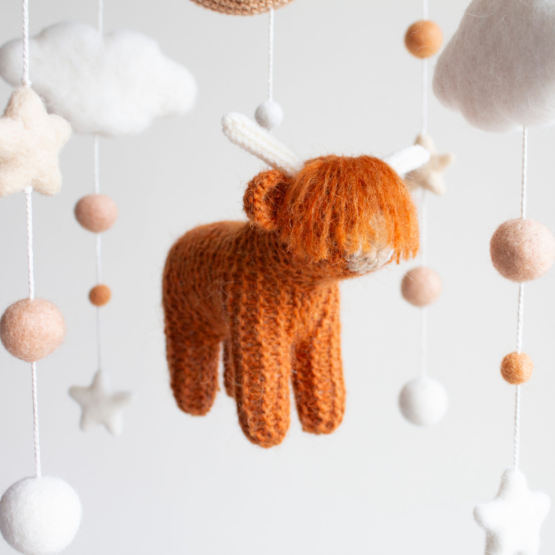 Detail of hand-knitted burnt orange Highland Cow with soft wool texture for nursery decor