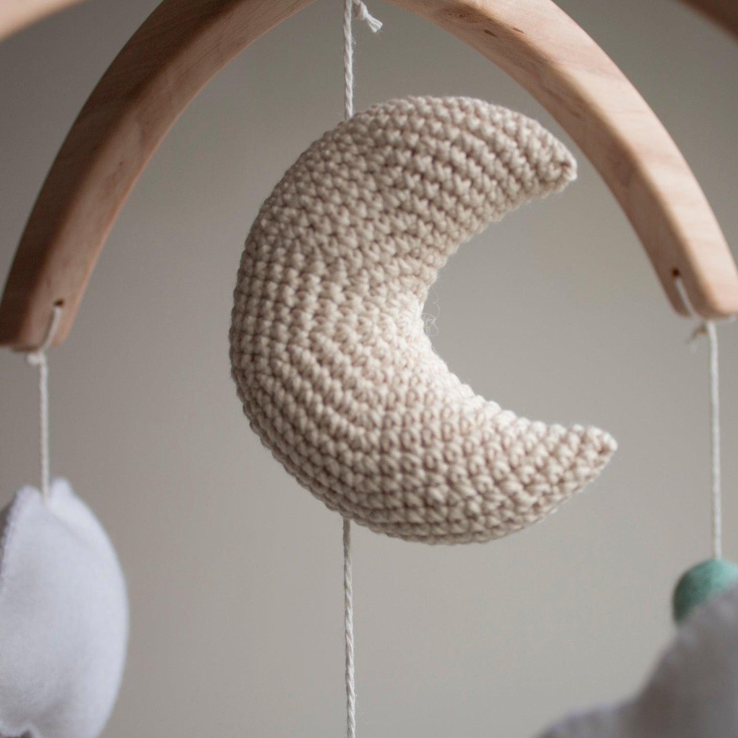 Intricate close-up of a beige crochet crescent moon with delicate white embroidery, part of the LanaCrocheting horse and cactus mobile set. Handcrafted with 10 years of expertise, this artisan moon is made from premium cotton to provide a safe and beautiful focal point above a baby's crib. A top choice for clients who prioritize uniqueness and useful gifting that transitions from nursery decoration to a cherished childhood heirloom.