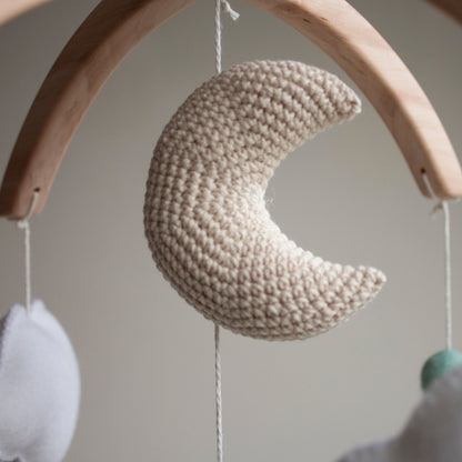Intricate close-up of a beige crochet crescent moon with delicate white embroidery, part of the LanaCrocheting horse and cactus mobile set. Handcrafted with 10 years of expertise, this artisan moon is made from premium cotton to provide a safe and beautiful focal point above a baby's crib. A top choice for clients who prioritize uniqueness and useful gifting that transitions from nursery decoration to a cherished childhood heirloom.