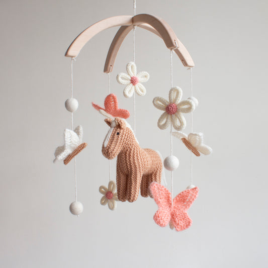 Decorative baby mobile with a knitted tan horse, flowers, and butterflies 